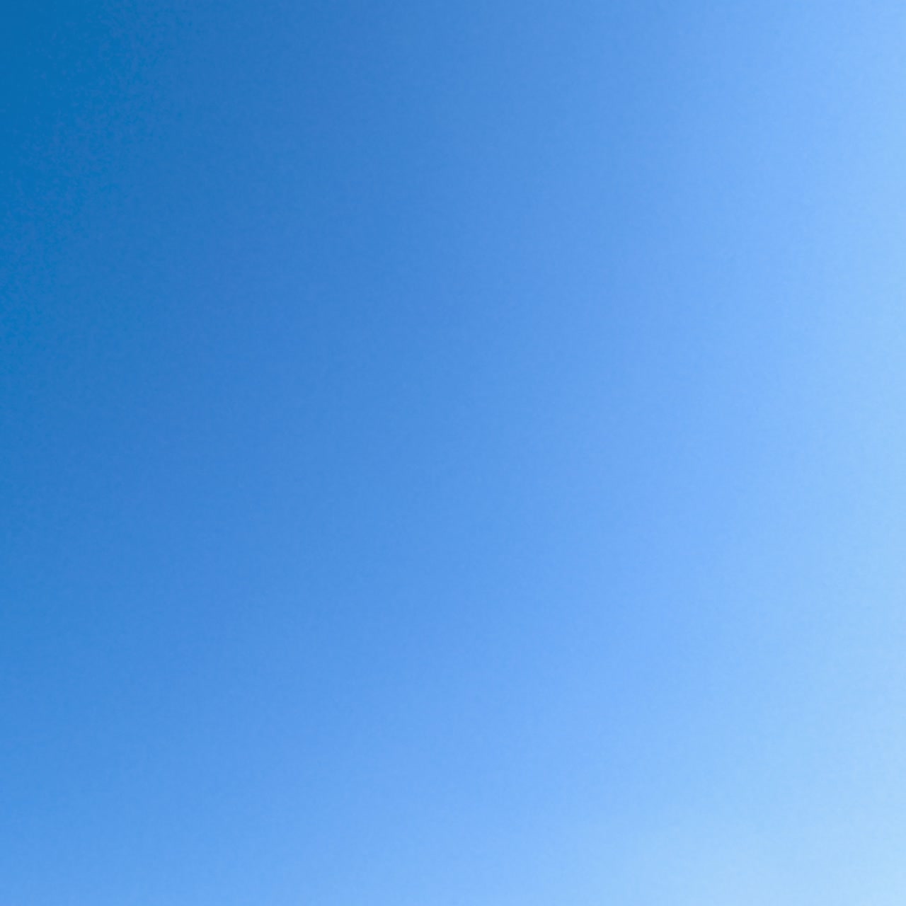 Blauer, sonniger Himmel klärt sich von weißen Wolken auf. Leichte Schneewehen ziehen schnell am Horizont vorbei und verschwinden aus dem Blickfeld