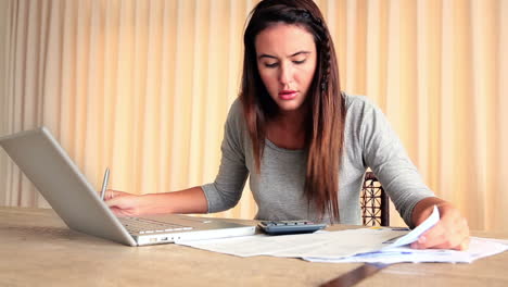 Stressed-brunette-working-out-her-finances-with-laptop