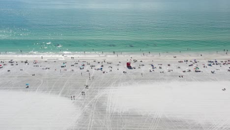 people chilling on white sand of wide siesta key beach, beach is groomed and ocean water is turquoise