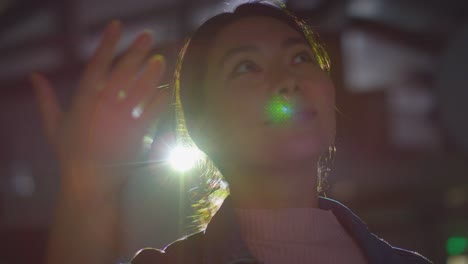 close up of woman visiting and interacting with immersive art exhibition backlit by light from projector 7