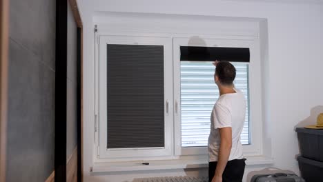 man installing pleated blinds on an interior window