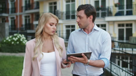 Entrepreneurs-using-tablet-computer-at-street.-Business-couple-walking-together