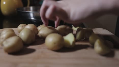 female slowly cutting the potato in a haft on a cutting board - close up shot