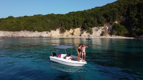 Happy-Young-Couple-Jumping-to-Water-from-a-Boat-Enjoying-Sunny-Holidays,-Mediterranean,-Greece