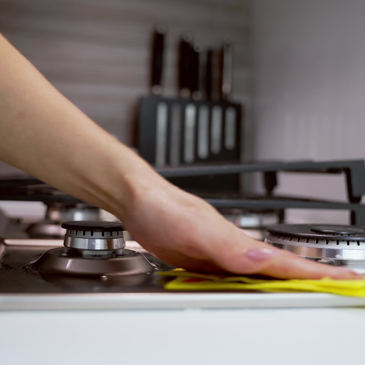 Woman's hand cleaning metal cooker. Cleaning gas stove in the kitchen. Pure surface of a gas cooker. Householding concept. Close-up.