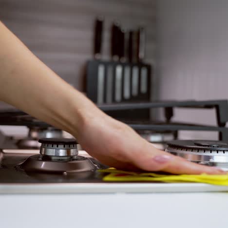 woman's hand cleaning metal cooker. cleaning gas stove in the kitchen. pure surface of a gas cooker. householding concept. close-up.