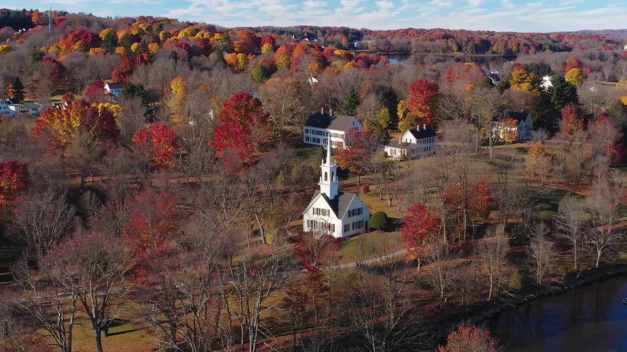 Aerial video captures a quaint village church amidst vibrant autumn foliage