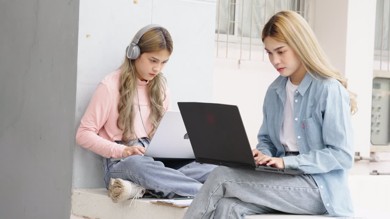 Two Asian girls student partners are working on a laptop help study together