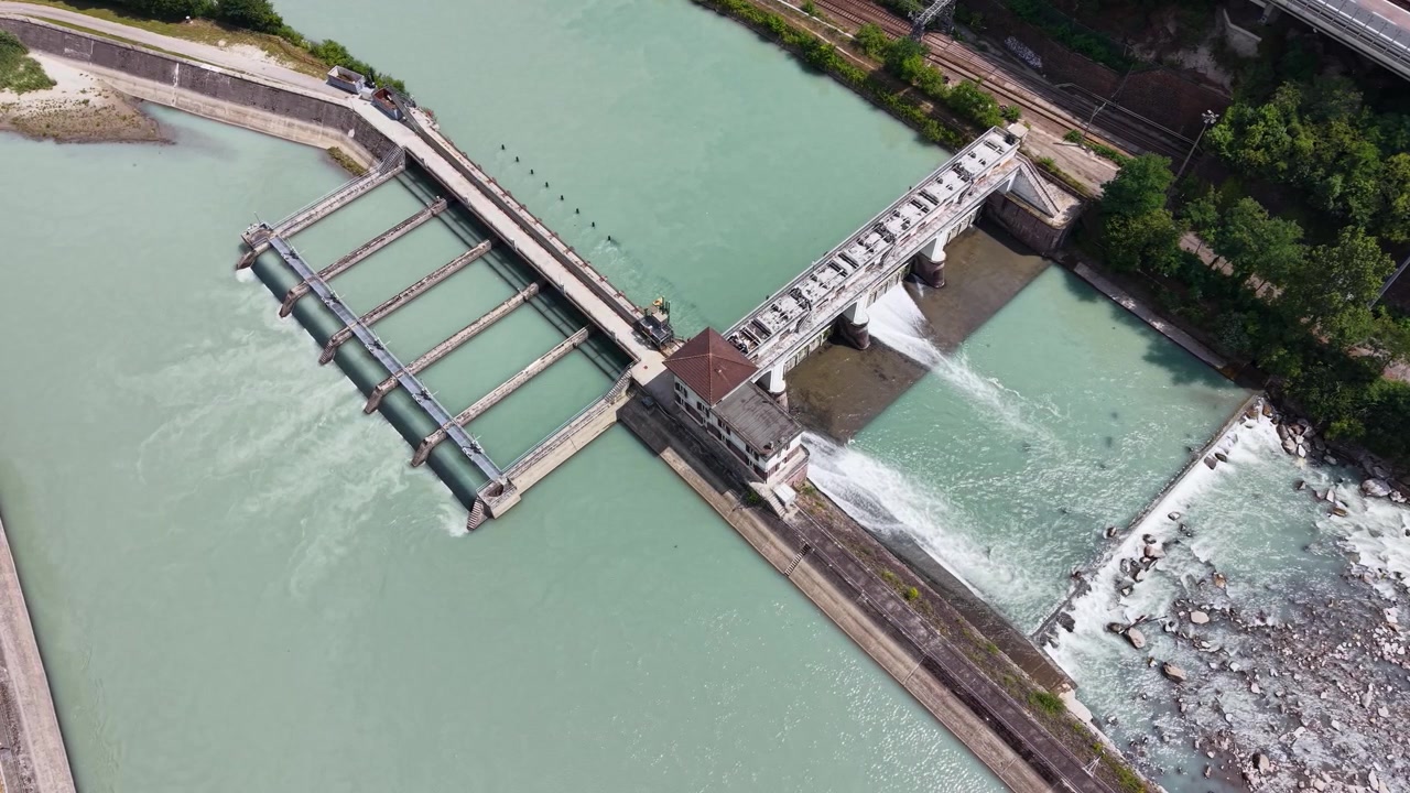 Vista de dron de la central hidroeléctrica de Ponte Gardena con agua fluyendo, infraestructura de la presa y el río Isarco en el norte de Italia