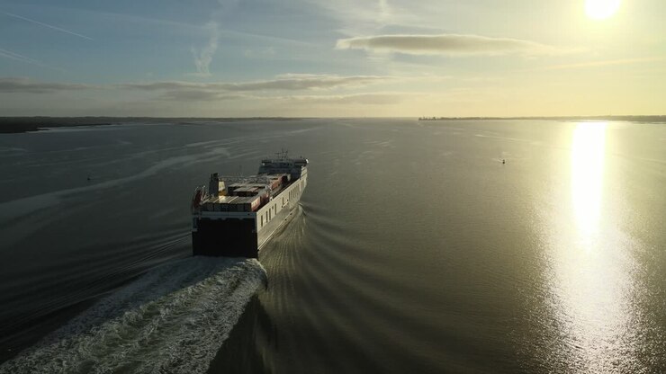 Cargo ship sailing at sunrise on calm waters on Carlingford Lough near Dundalk, County Louth, Ireland, aerial view