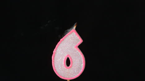 six birthday candle flickering and extinguishing on black background