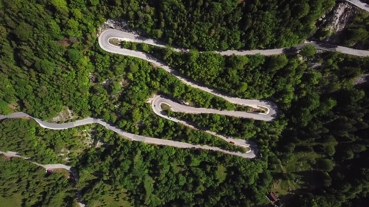 toma de drones, vista superior, de una carretera rural eslovena rodeada por un bosque de montaña