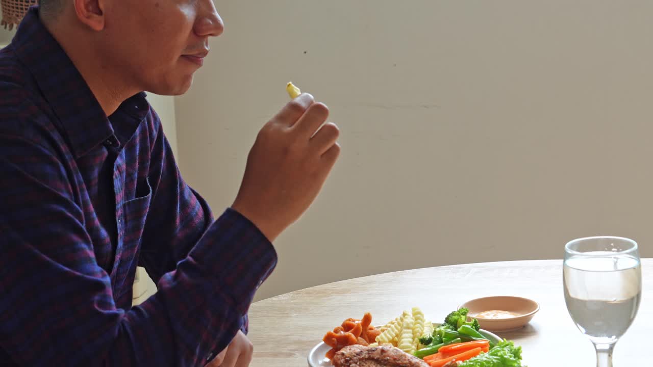Person enjoying a meal of steak, vegetables, and french fries