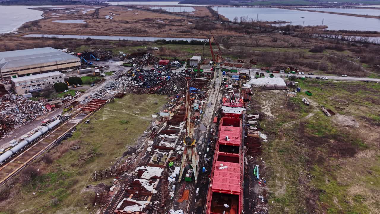 Attività in cantiere navale con navi e gru per operazioni di trasporto.