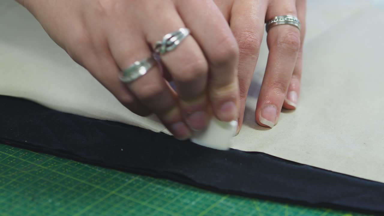 una mujer marcando tela con chack al lado de la plantilla