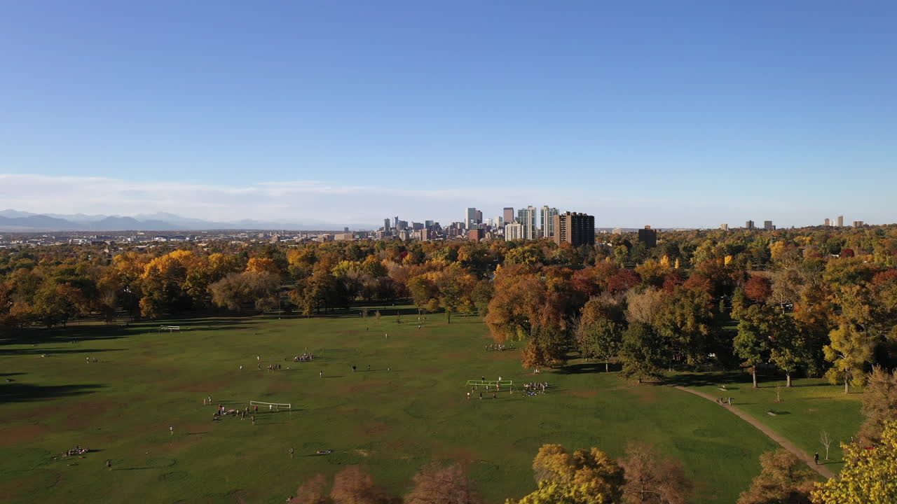 가을철 도시 공원 덴버의 탁 트인 전망, 나무와 호수가 있는 도시 녹색 잔디 놀이터에 있는 사람들, 지평선의 도시 경관