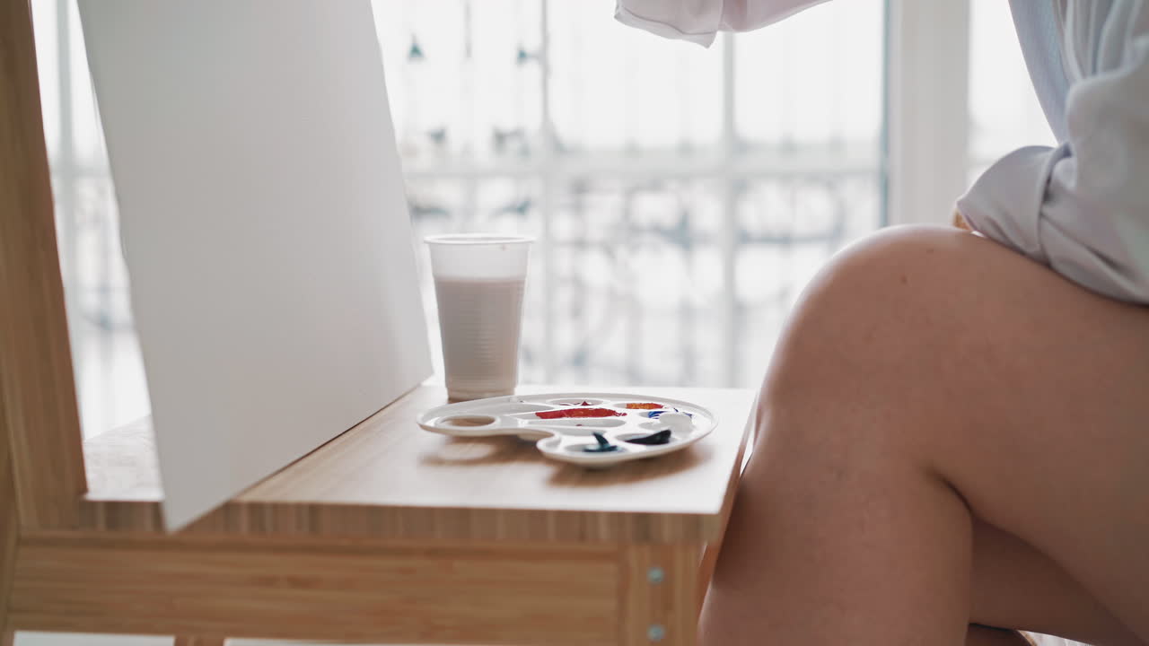 mujer artista dibuja tomando pintura de la paleta con pincel