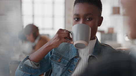 beautiful african american business woman drinking coffee chatting to colleague enjoying conversation in office workplace