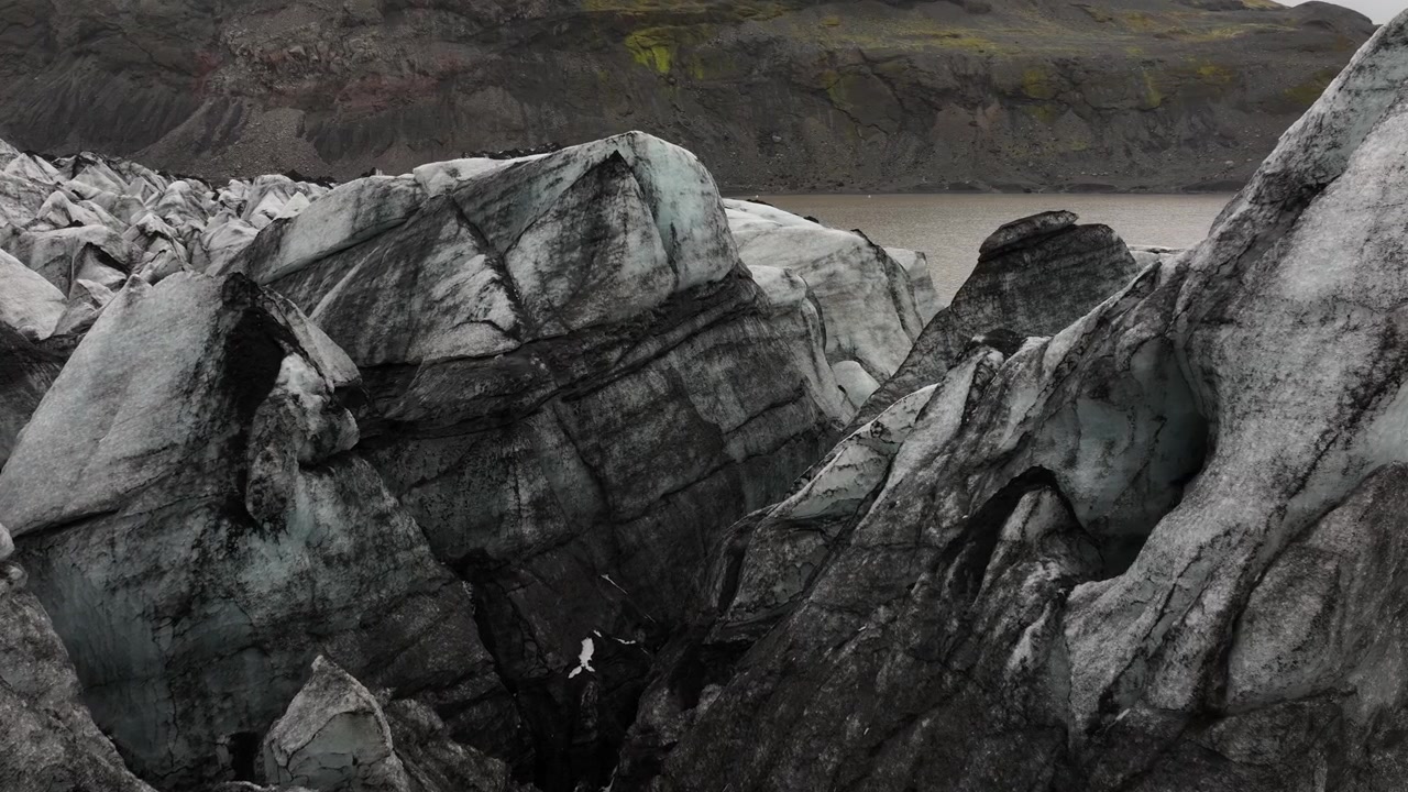 Detaljeret udsigt over brudte isformationer på overfladen af Sólheimajökull-gletsjeren på Island, der fremhæver de dybe sprækker og ru teksturer