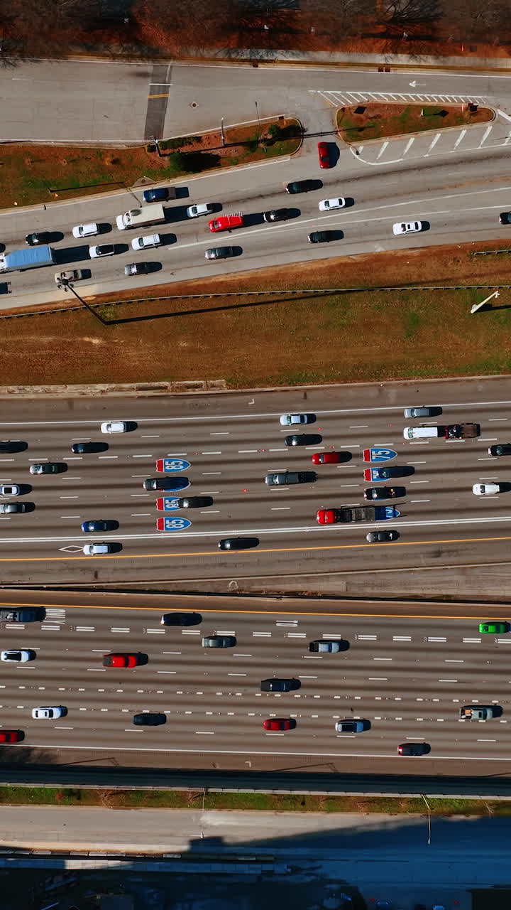 Numerous cars and lorries move to both sides of the road. Top view on the speedway on daytime. Vertical video