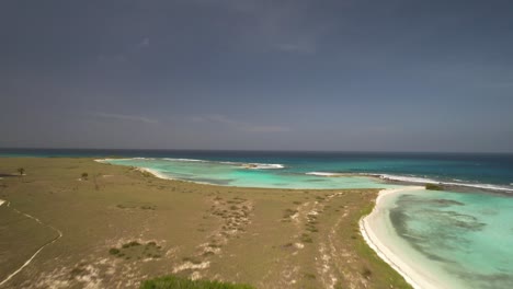 Tropical-Los-Roques-archipelago-in-Venezuela-with-clear-turquoise-waters,-white-sands-and-scattered-buildings,-aerial-view