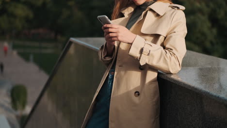 caucasian female student using smartphone outdoors.