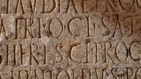 tight shot of carved words in stone panel at ancient roman ruins at the archaelogical unesco heritage site of volubilis in morocco.