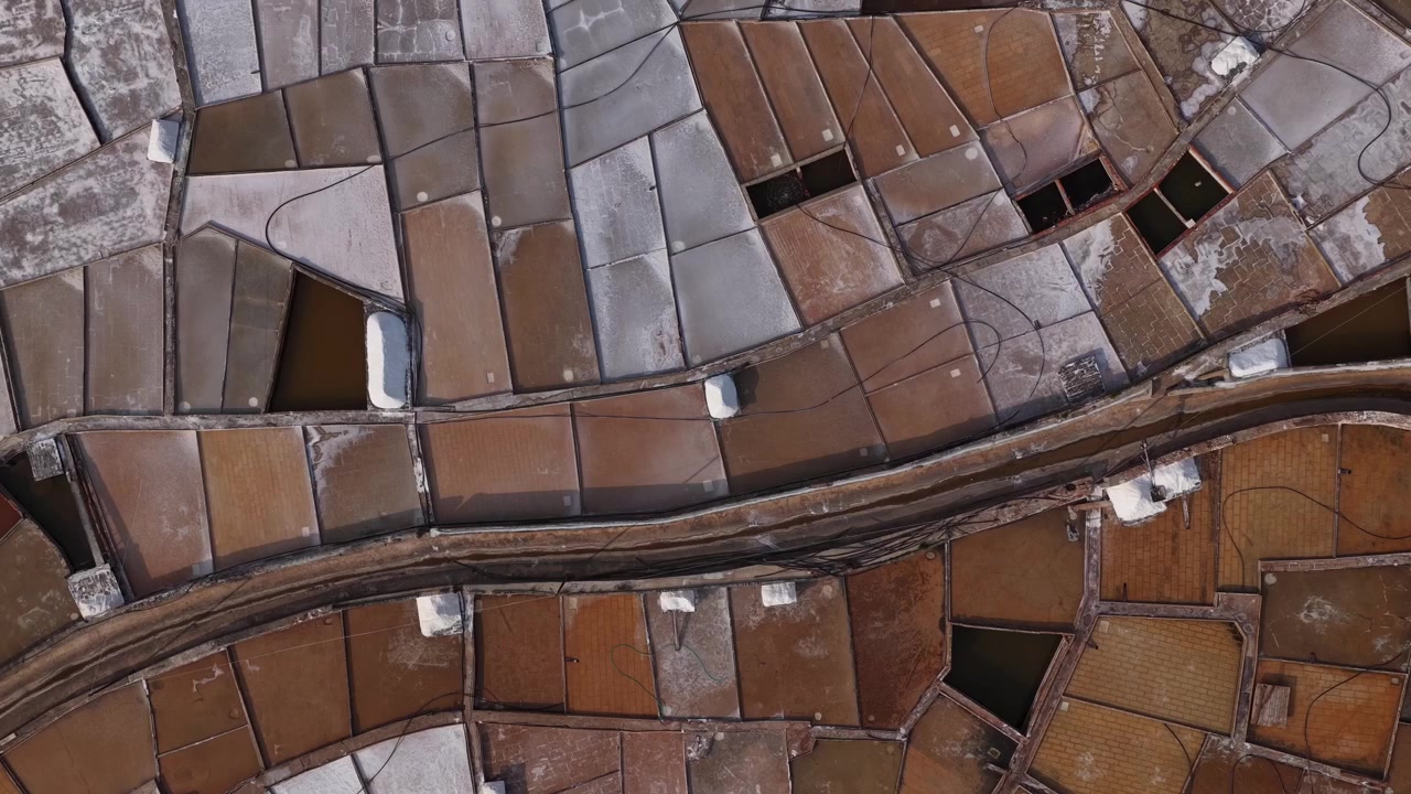 Drone shot of Rio Maior salt pans reveals geometric patterns, earthy tones, and mineral textures of rare inland salt flats under daylight.