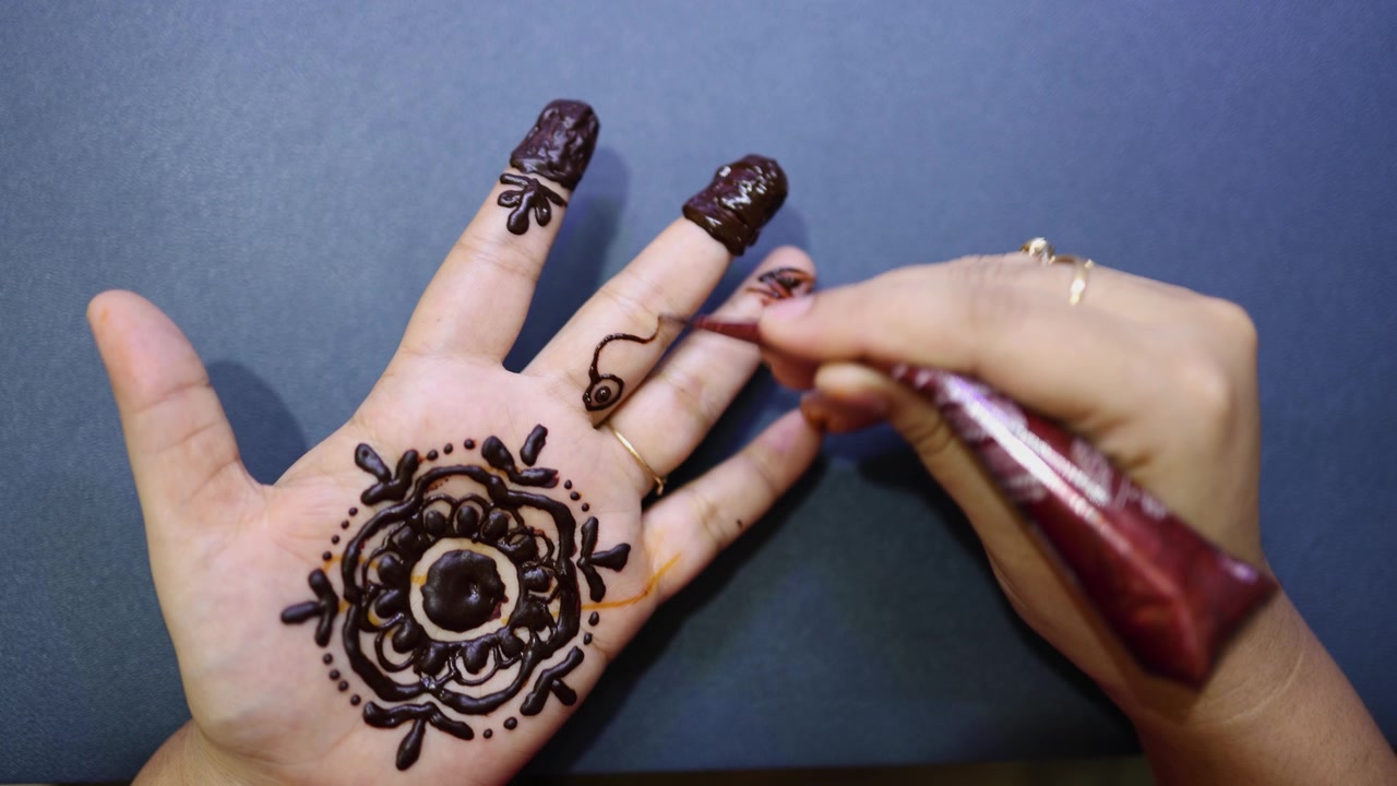 Applicazione di intricato disegno all'henné Mehndi sul palmo durante una celebrazione indiana
