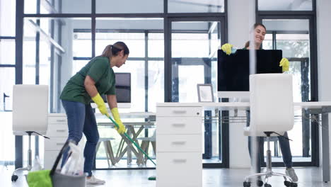 two young women dancing while cleaning an office