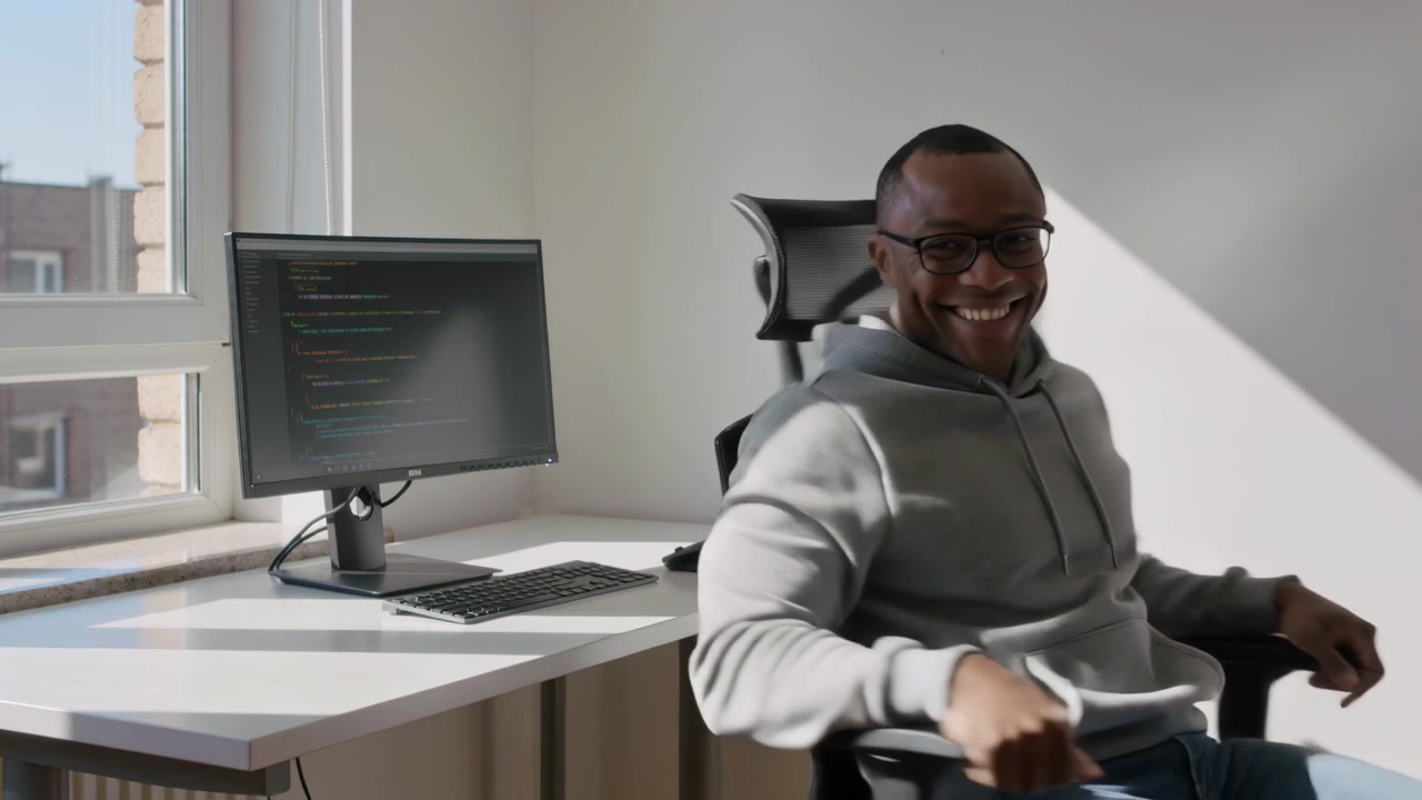 Seeing alert, man wearing hoodie turning to camera from monitor showing code at office, copy space