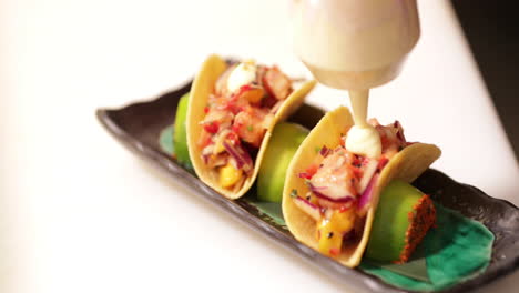 chef putting mayonnaise on top of sushi tacos using a squeeze bottle