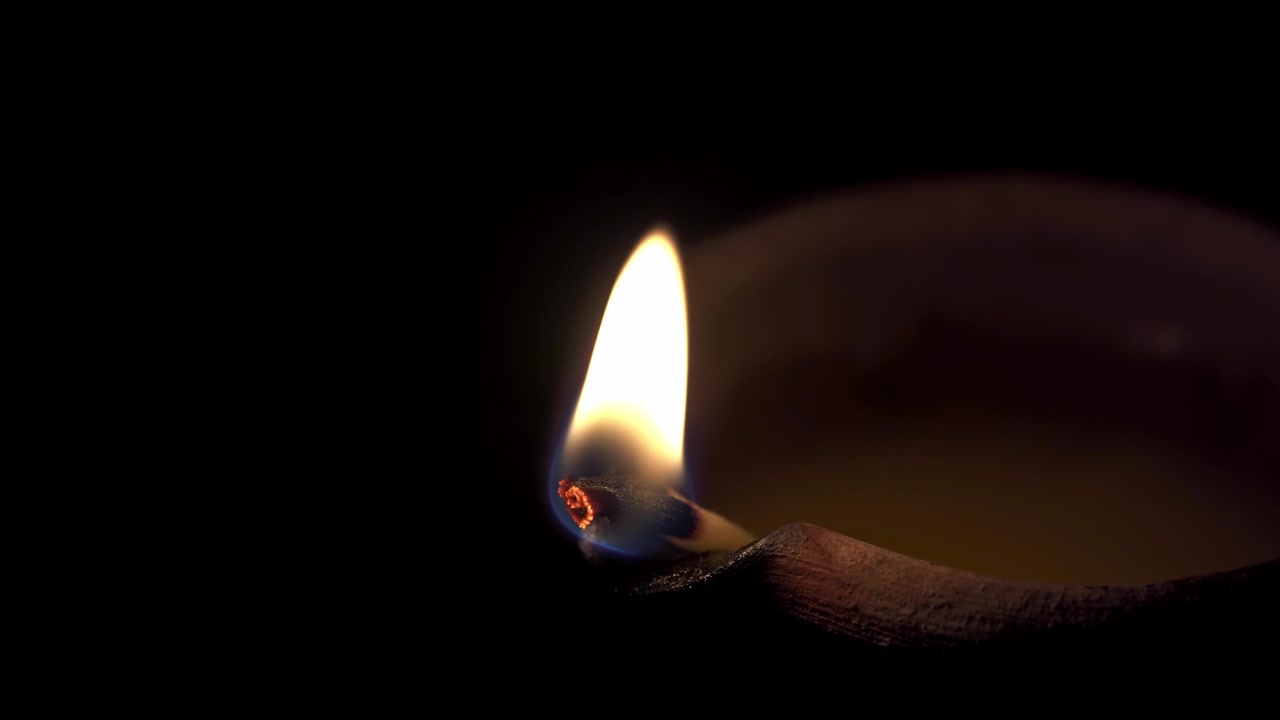 Primo piano di una lampada a olio tradizionale in terracotta accesa al buio