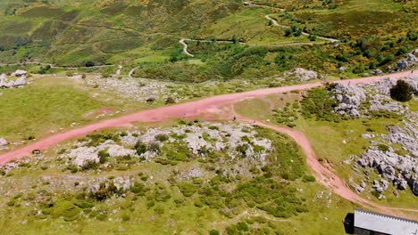 People stand on the ground road on the top of the mountain. A fence protects the tourist at the rock precipice. Arial view.