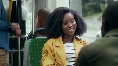 young pretty girl with curly hair talking cheerfully with a man who sitting next to her in the tram while their going somewhere together