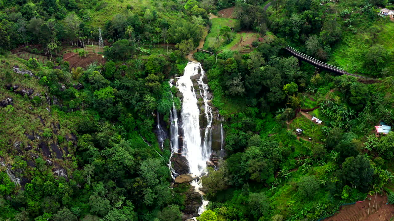 Un drone sale accanto a una cascata vicino a Ella, Sri Lanka, rivelando la lussureggiante foresta circostante e l'altezza spettacolare delle cascate