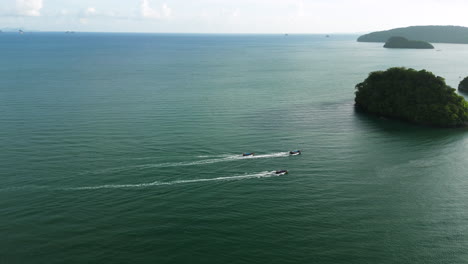 Tourist-boats-sail-towards-forested-rocky-island-in-Ao-Nang,-Thailand