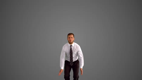 businessman jumping and doing the splits on grey background