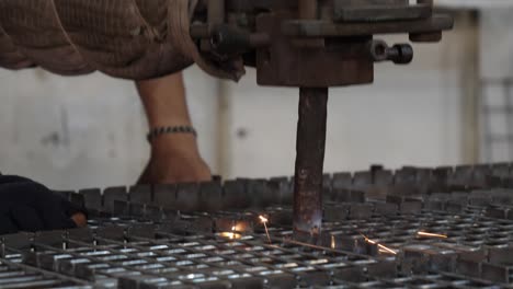 close up of arm head of spot welding machine creating sparks on wire mesh frame in factory