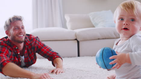 Young-father-lying-on-floor-playing-with-toddler-son-at-home