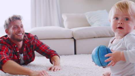 young father lying on floor playing with toddler son at home