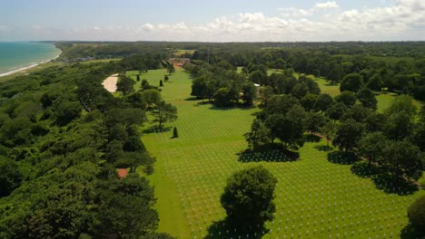 un vuelo de avión no tripulado sobre el cementerio y monumento americano de normandía, con filas de cruces blancas que marcan las tumbas de los soldados estadounidenses caídos durante la invasión de normandia en omaha y la playa de utah el día d de 1944.