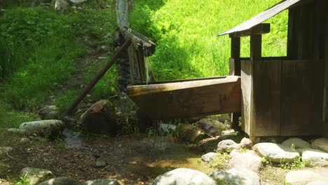 Fresh-Water-Being-Collected-Into-Traditional-Wooden-Bucket-And-Poured-Into-Ground-In-Shirakawago