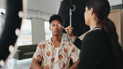 makeup artist applying makeup to model in studio