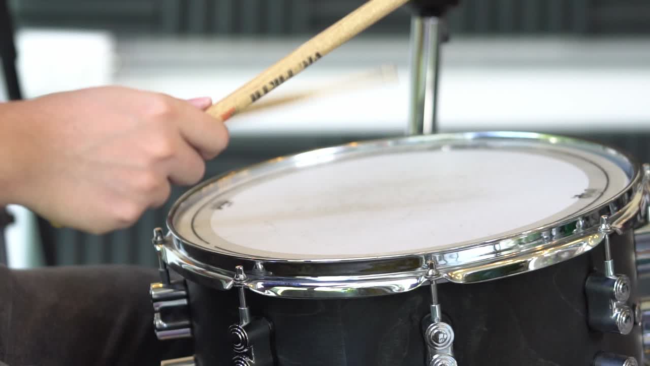 drum stick hitting a gray tom drum in slow motion close up