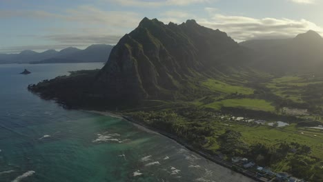 vista aérea del rancho y valle de kualoa con la montaña icónica vista sobre el océano pacífico turquesa durante la puesta de sol