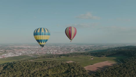 4k-Antenne-Zwei-Heißluftballons-über-Weinbergen-Mit-Stadt-Im-Hintergrund