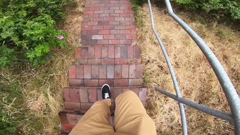 man's feet wearing sneakers walking down the narrow stairs outdoor - handheld shot