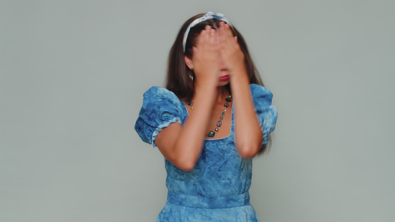Pretty young woman closing eyes with hand showing stop gesture, confused shy scared to watch, awful