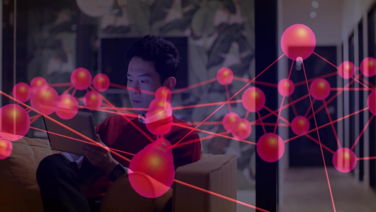 Seated man tapping tablet, viewing tech red-node overlay shifting over people as woman walking hall